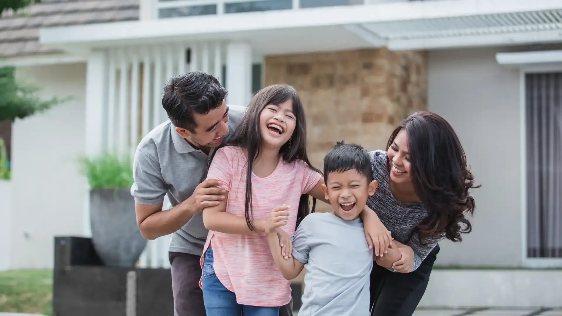 A family smiling in front of their new construction home.