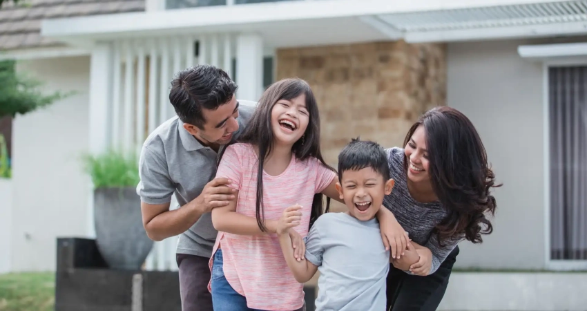 A family having fun in front of their new house