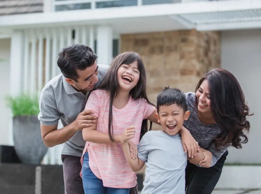 A family having fun in front of their new house