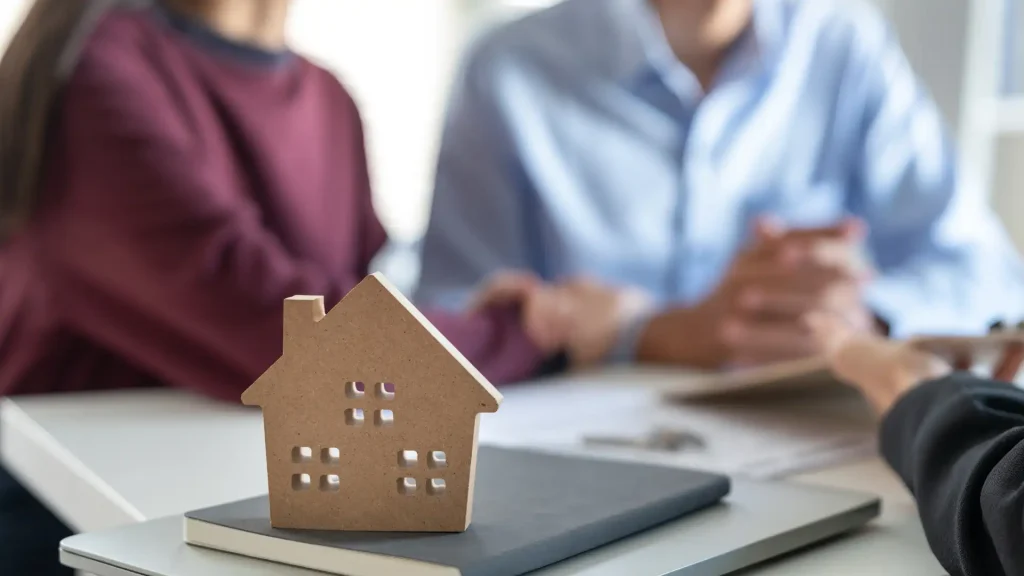 a house model is placed on a table and two people are talking to an accountant.