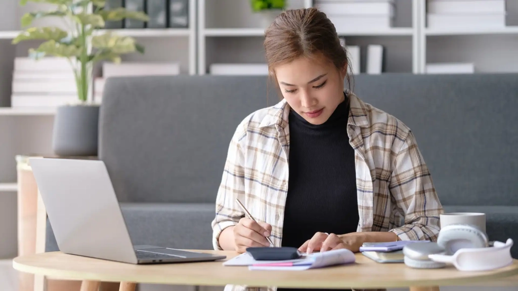 a person using a calculator and a pen in front of their laptop